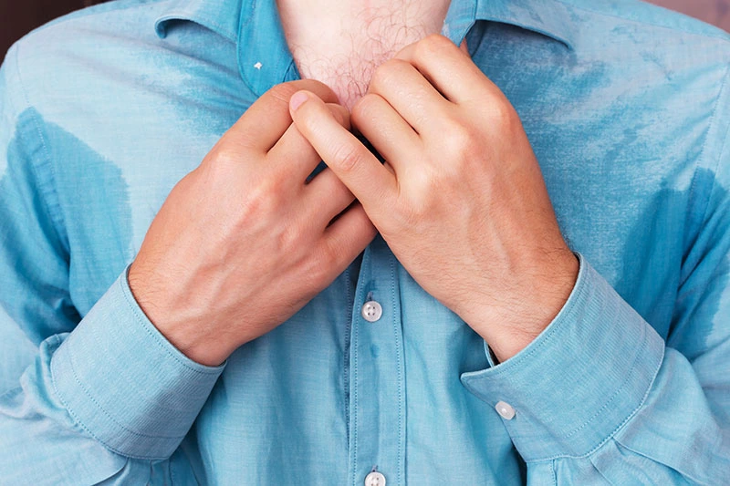 Person clutching shirt collar during night sweats