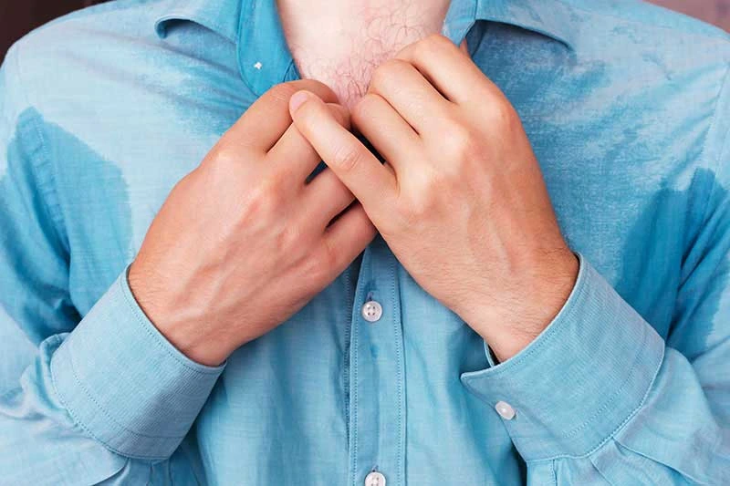Person clutching shirt collar during night sweats
